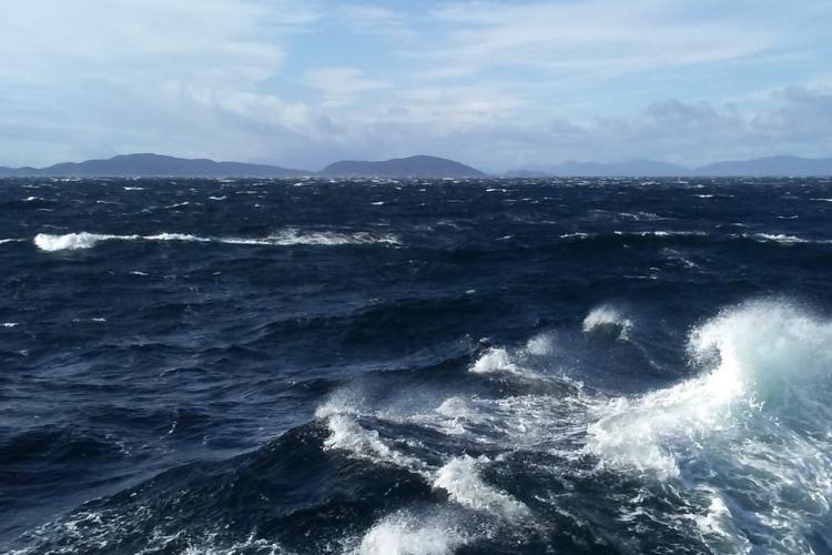Rough ocean with mountains in the background. 